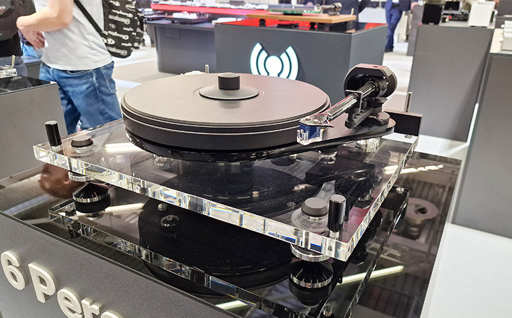 The 6 Perspex turntable at the Munich HiFi show in 2024 with a man in a white t-shirt and jeans visible behind it walking past