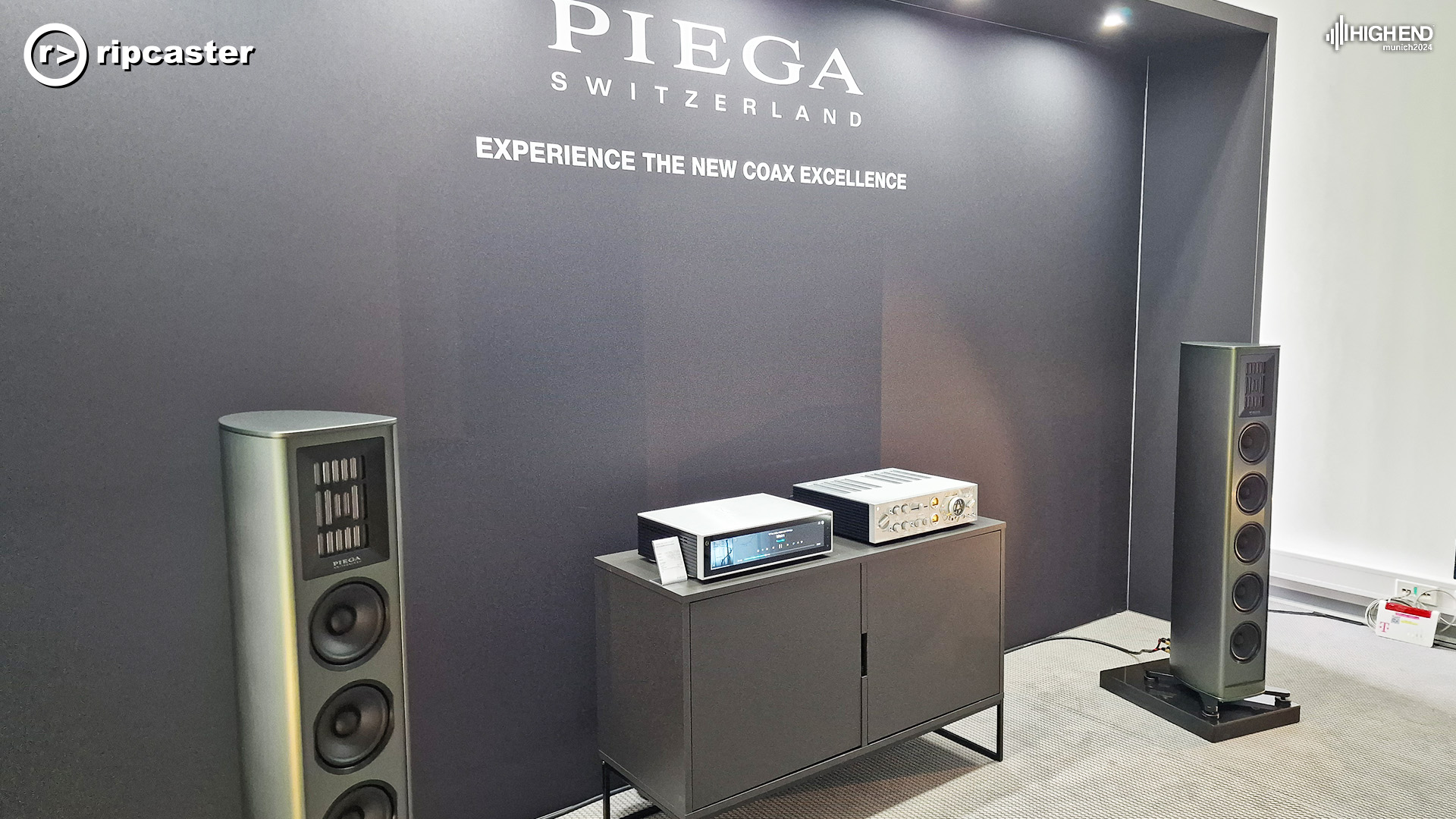 Piega floorstanding speakers in grey with HiFi Rose equipment between them.