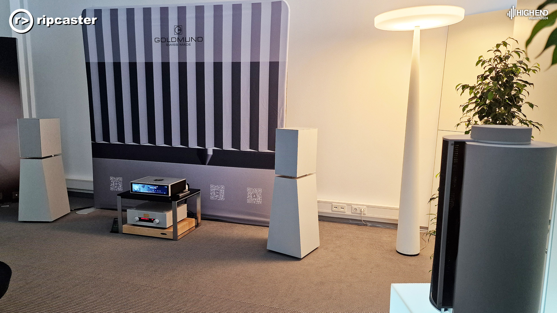 A pair of white speakers with a futuristic style lamp to the side.