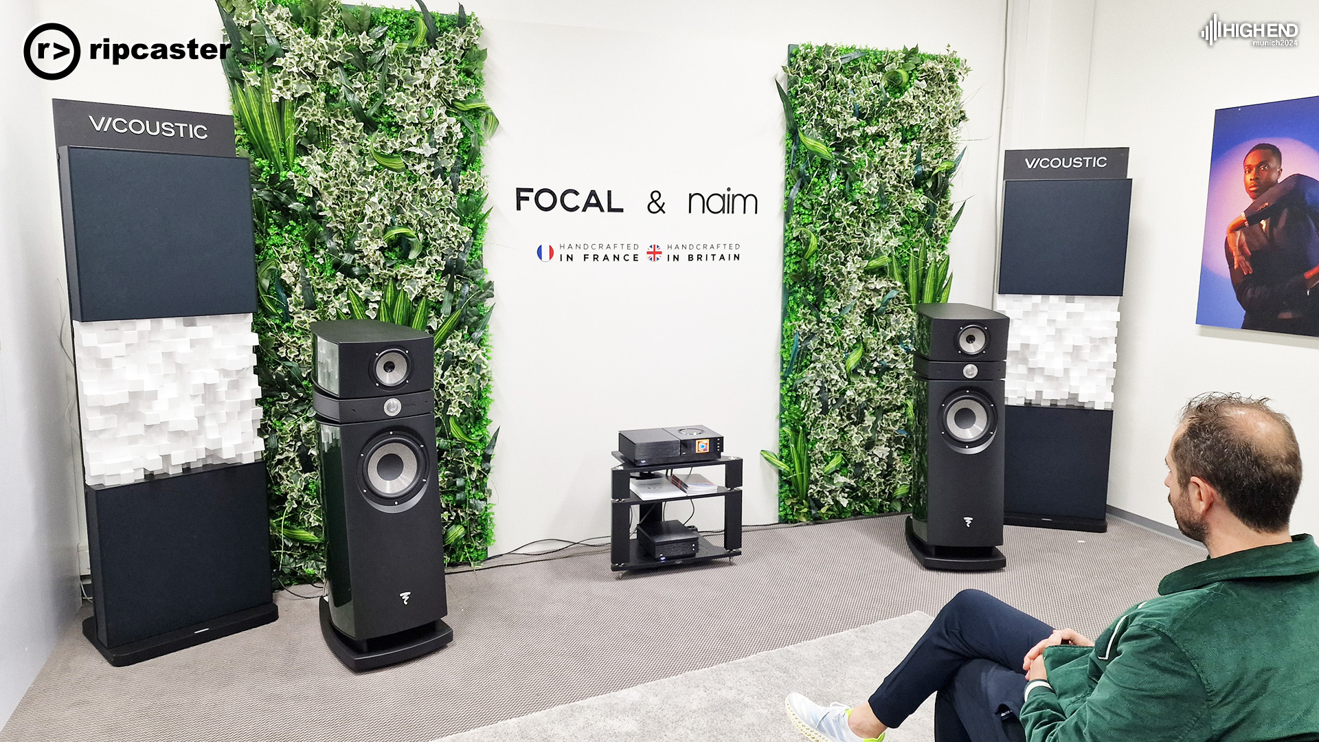 Focal and Naim - a pair of speakers with HiFi equipment between.  A man in a green jacket is in the foreground 