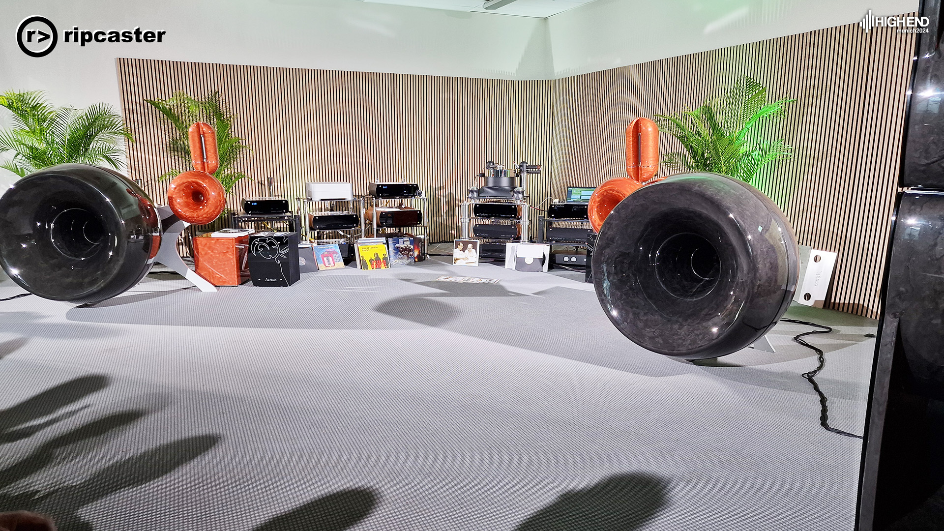 Very large speakers that look like car tyres and other orange speakers that a small car tyres with bit pointing upwards.  There's a lot of other HiFi equipment in the photo