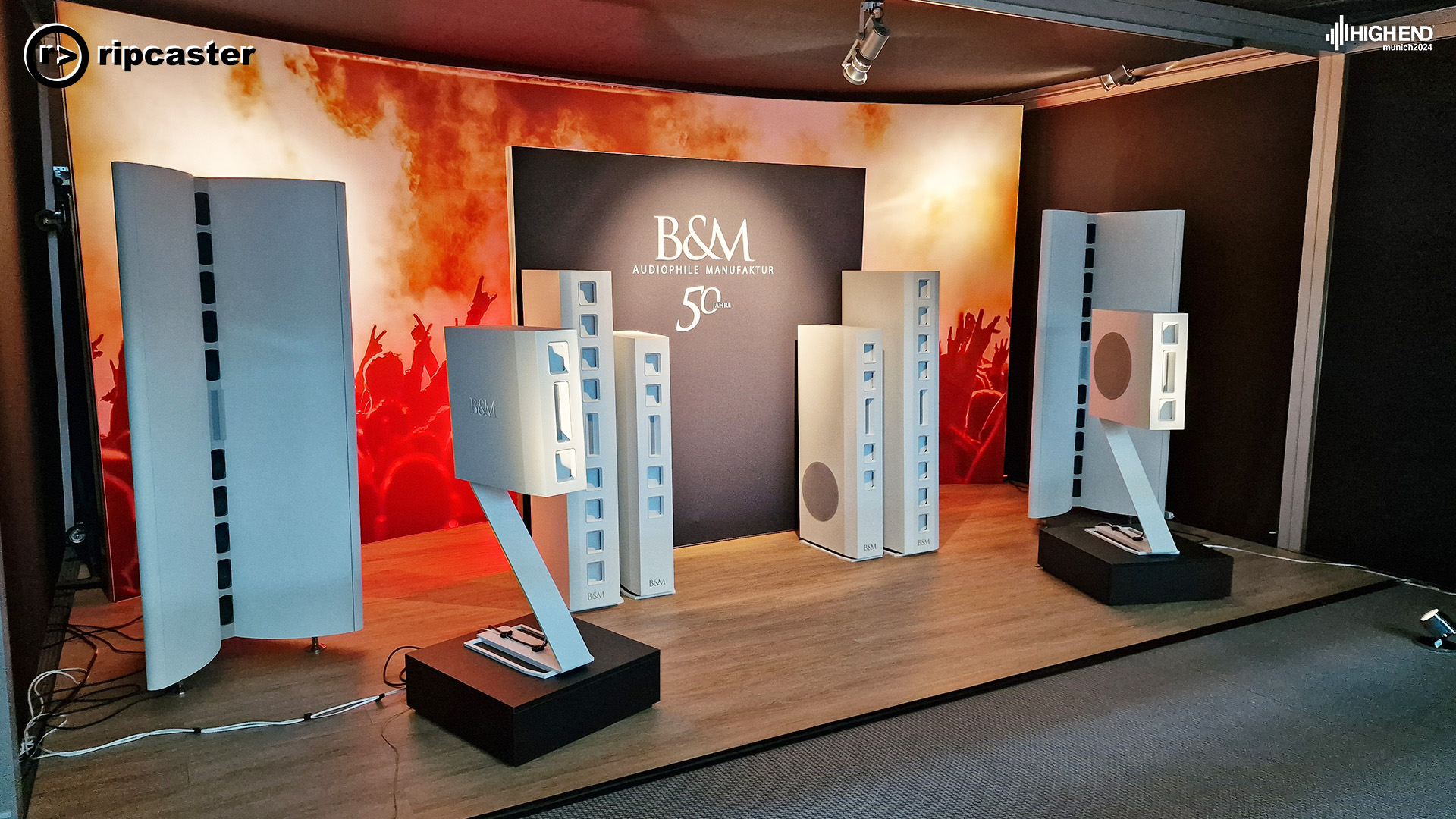 A lot of white floorstanding speakers together with some bookshelf white speakers on a stand.  This is B&M
