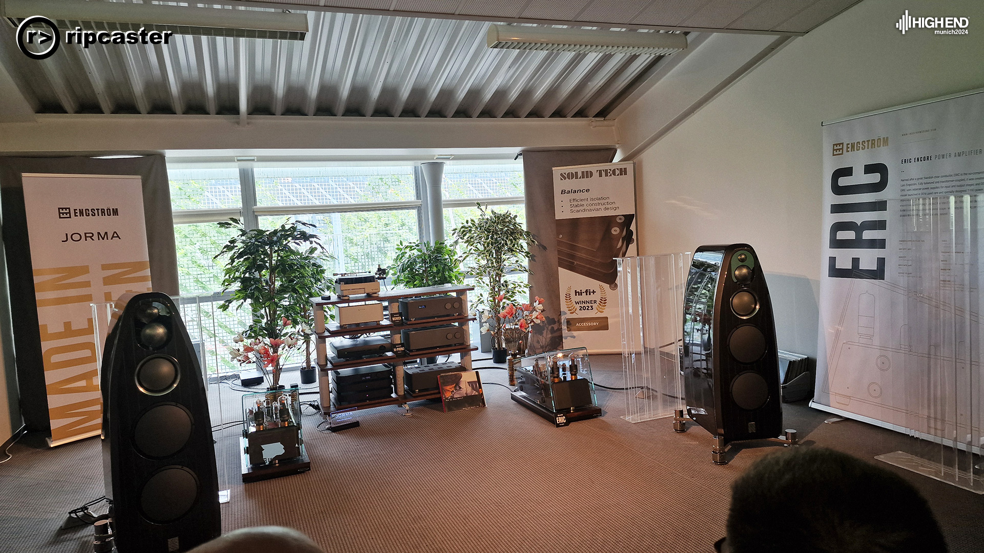 A pair of black floorstanding speakers with various pieces of HiFi kit also in the room.