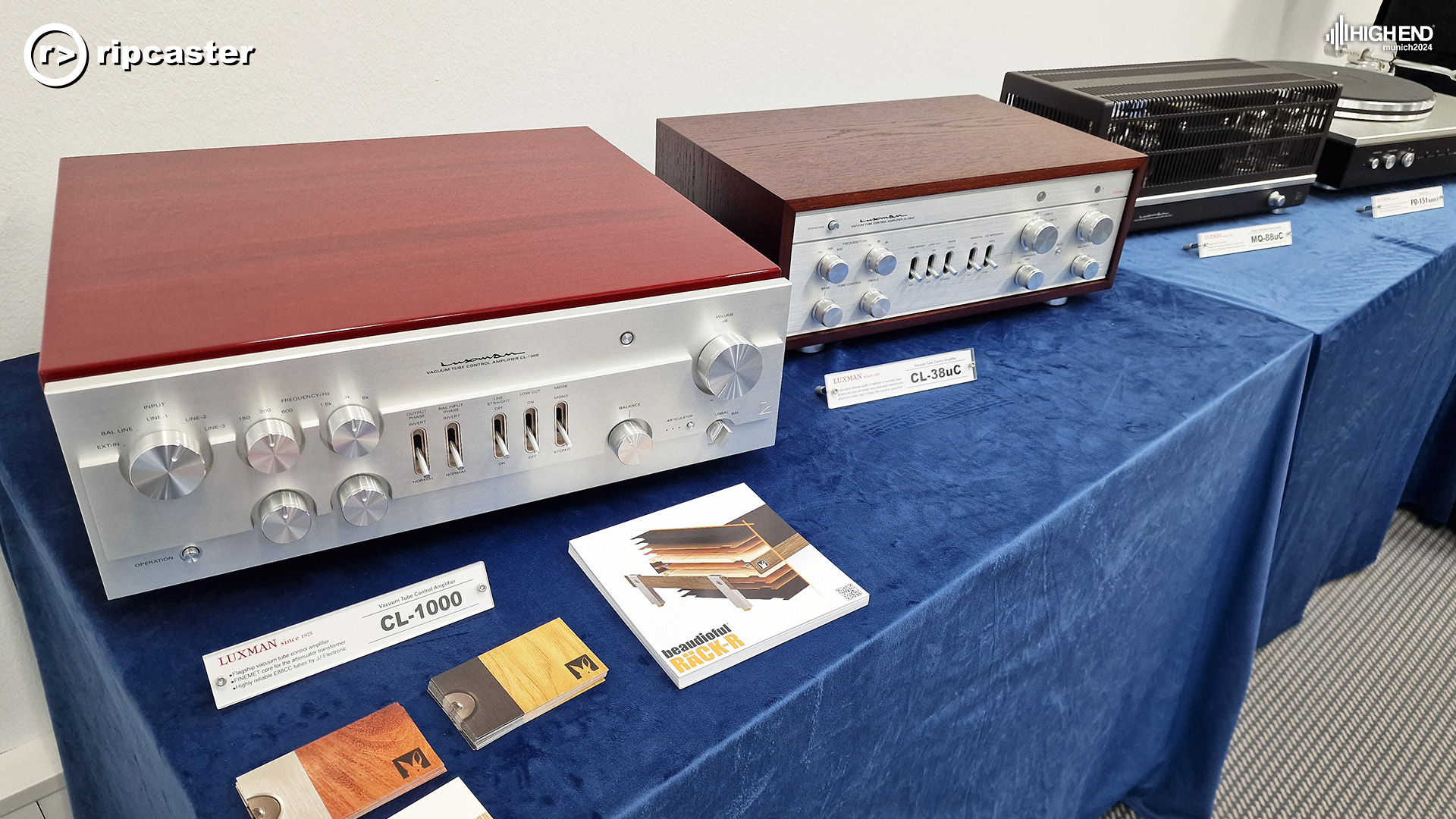 Luxman.  HiFi equipment lined up along a table with blue velvet draped over the table