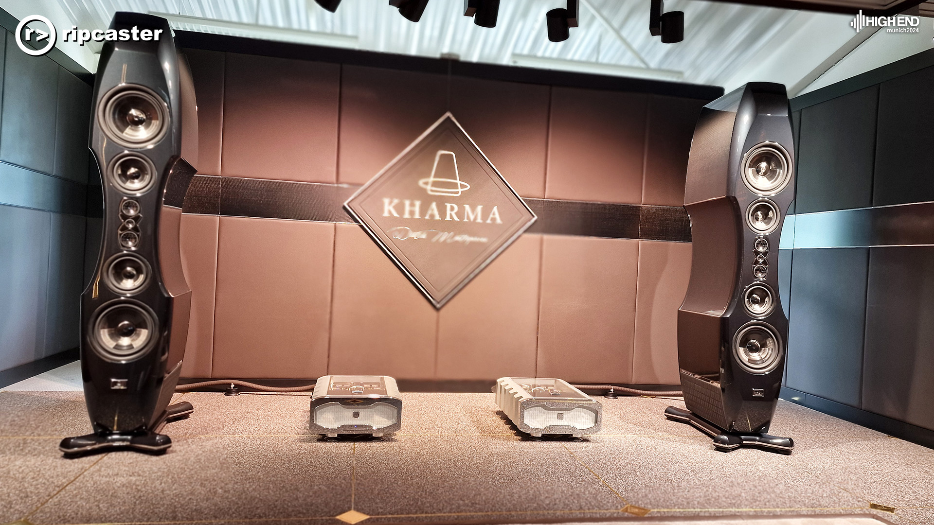 Kharma.  A pair of large black floorstanding speakers with HiFi equipment between them.