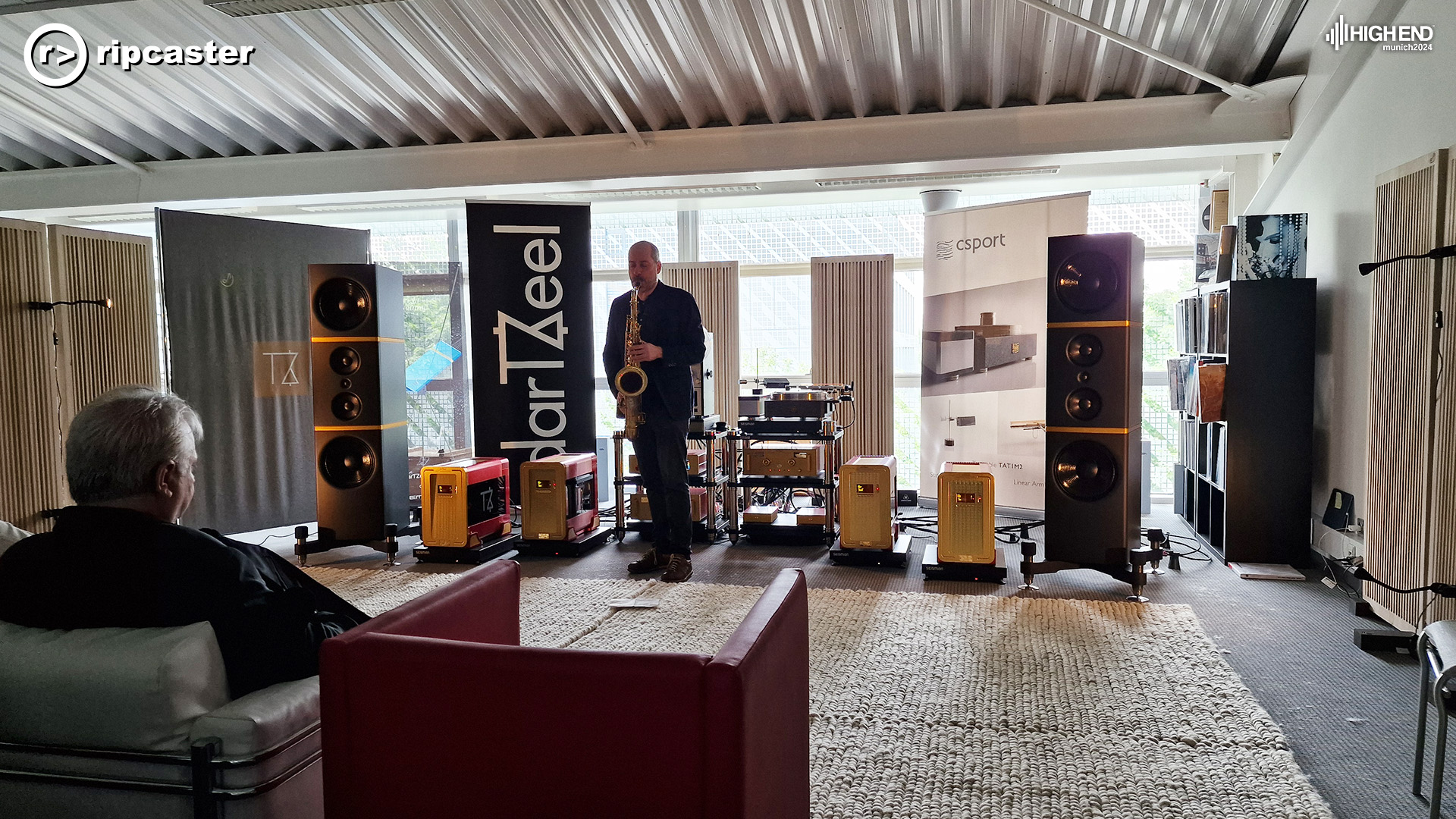 A man playing a saxaphone in front of various bits of HiFi equipment