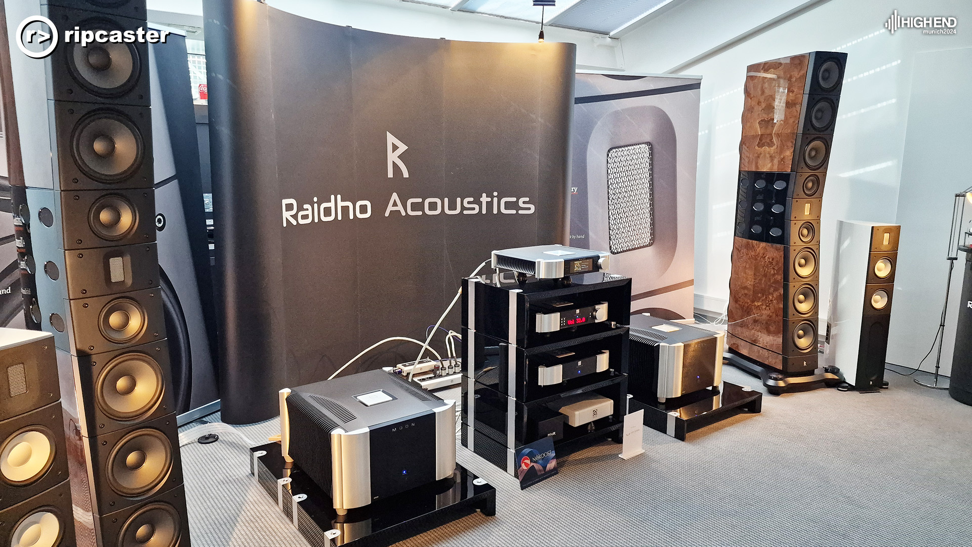 Raidho Acoustics.  There is MOON equipment between two very large speakers in a shiny, burl finish.  Either side of these two speakers are white Raidho speakers.