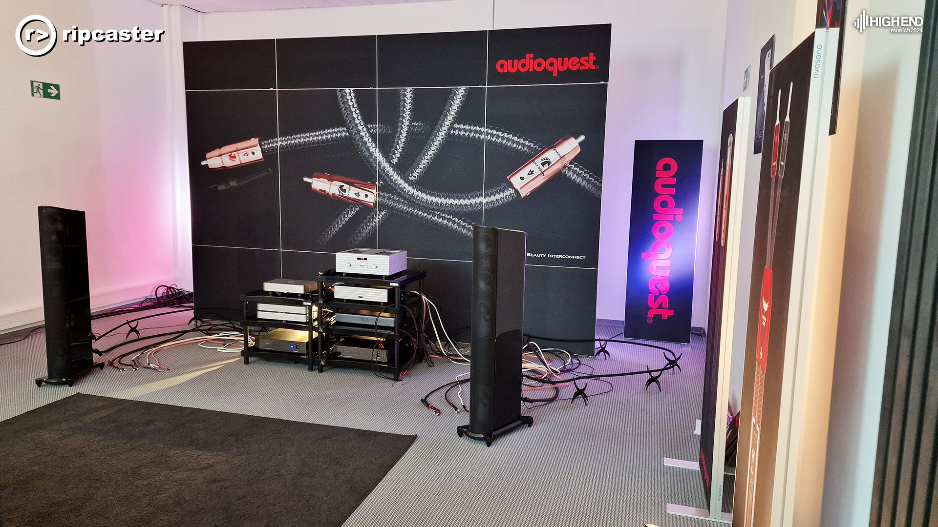 The Audioquest room with speakers and HiFi equipment at the front with large Audioquest signage at the back of the room.