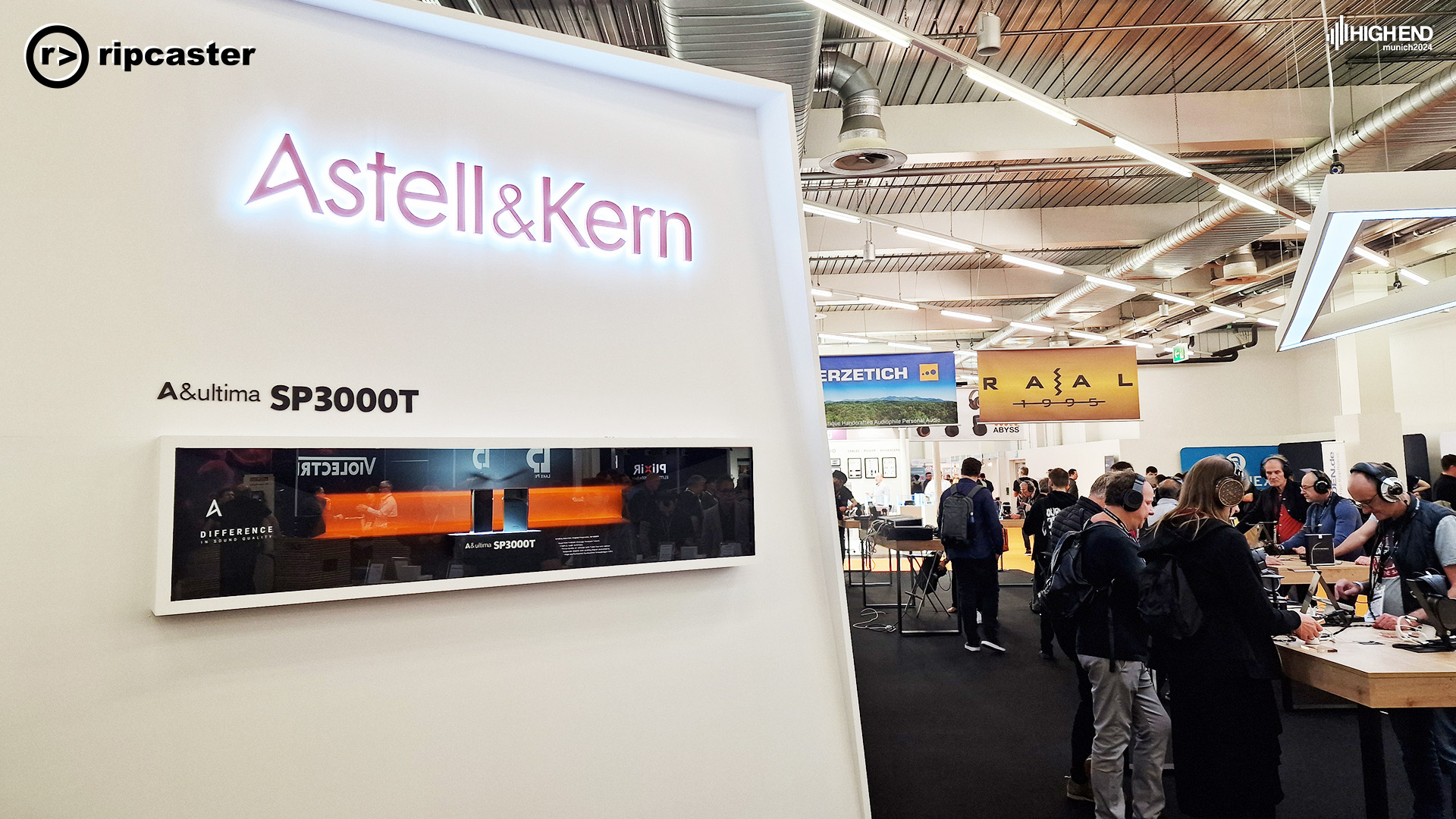 The sign for the Astell & Kern stand to the left with people in headphones to the right