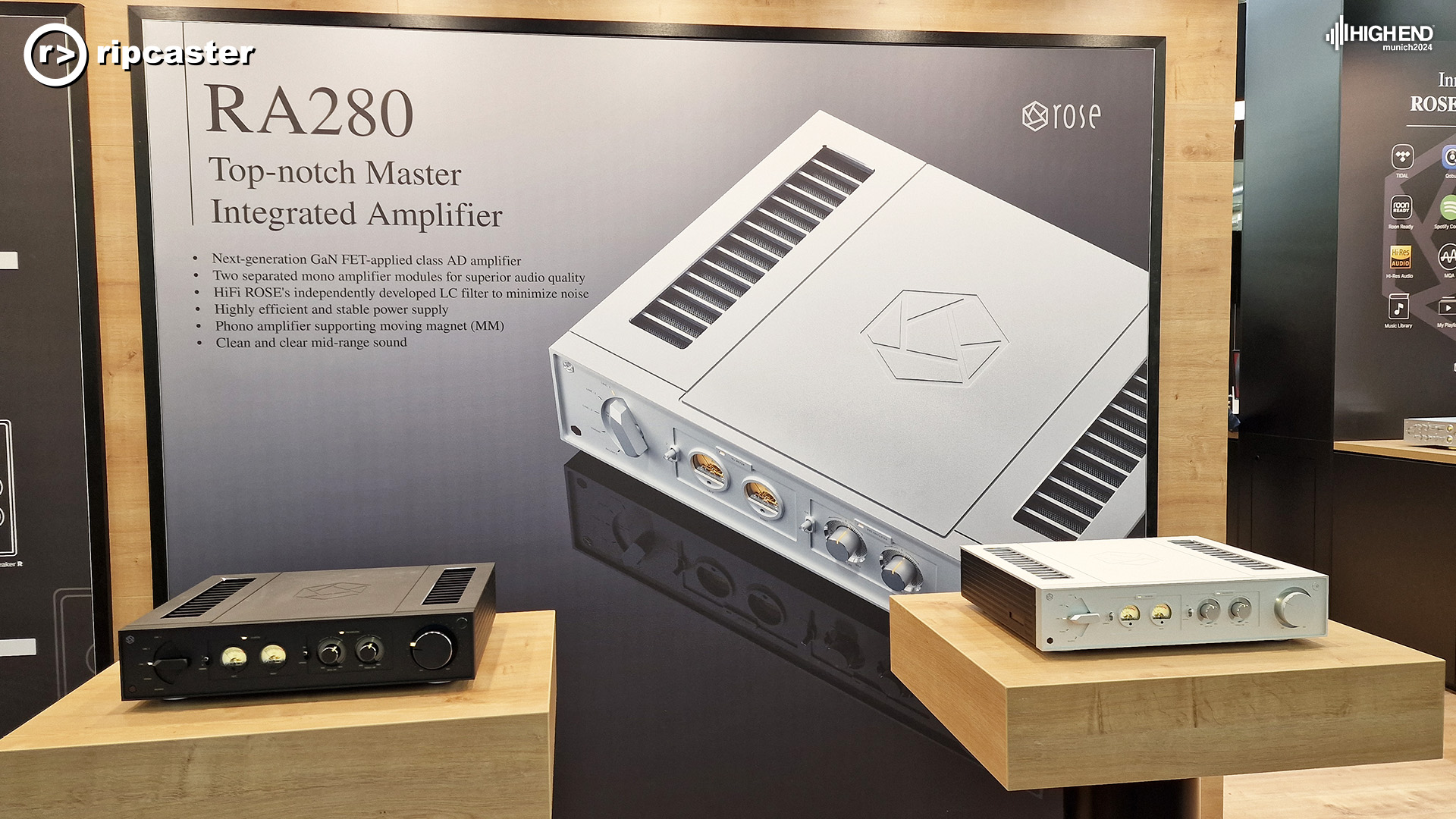 Two pieces of HiFi Rose equipment - the RA280.  The silver one to the right on a wooden stand and the black one to the left on a wooden stand.  There's a big sign behind with some key features listed