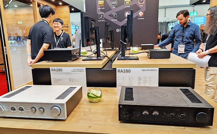 The HiFi Rose RA280 at the Munich HiFi Show.  The black on the right and the silver on the left.  There are men in the background.
