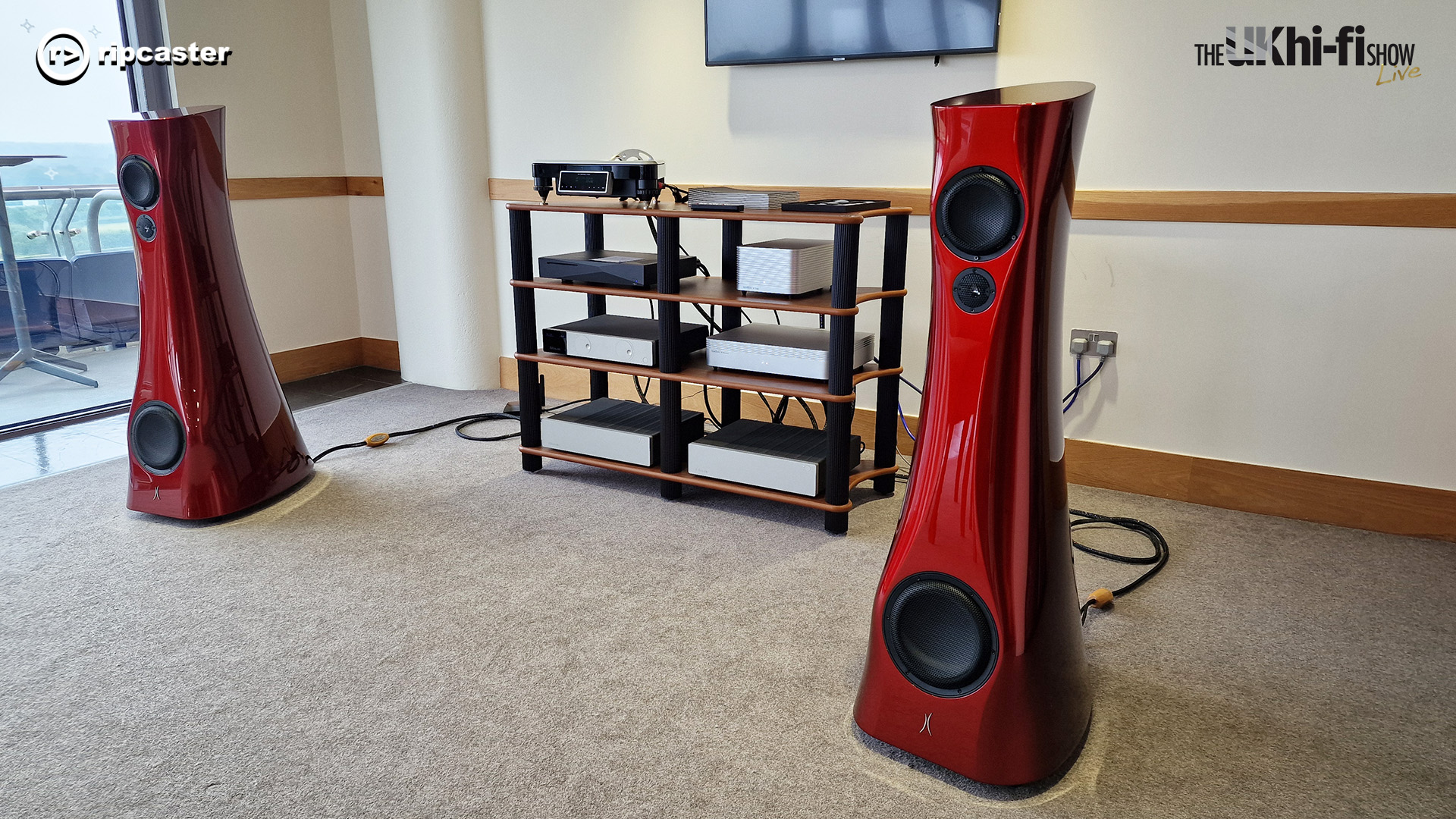 Estelon.  Two large red floorstanding speakers either side of some hifi equipment on a stand