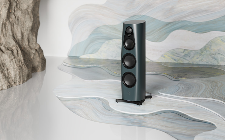 The Linn Triton finish 360 speaker on an arty, wavy background and floor with a rockface to the left of the image