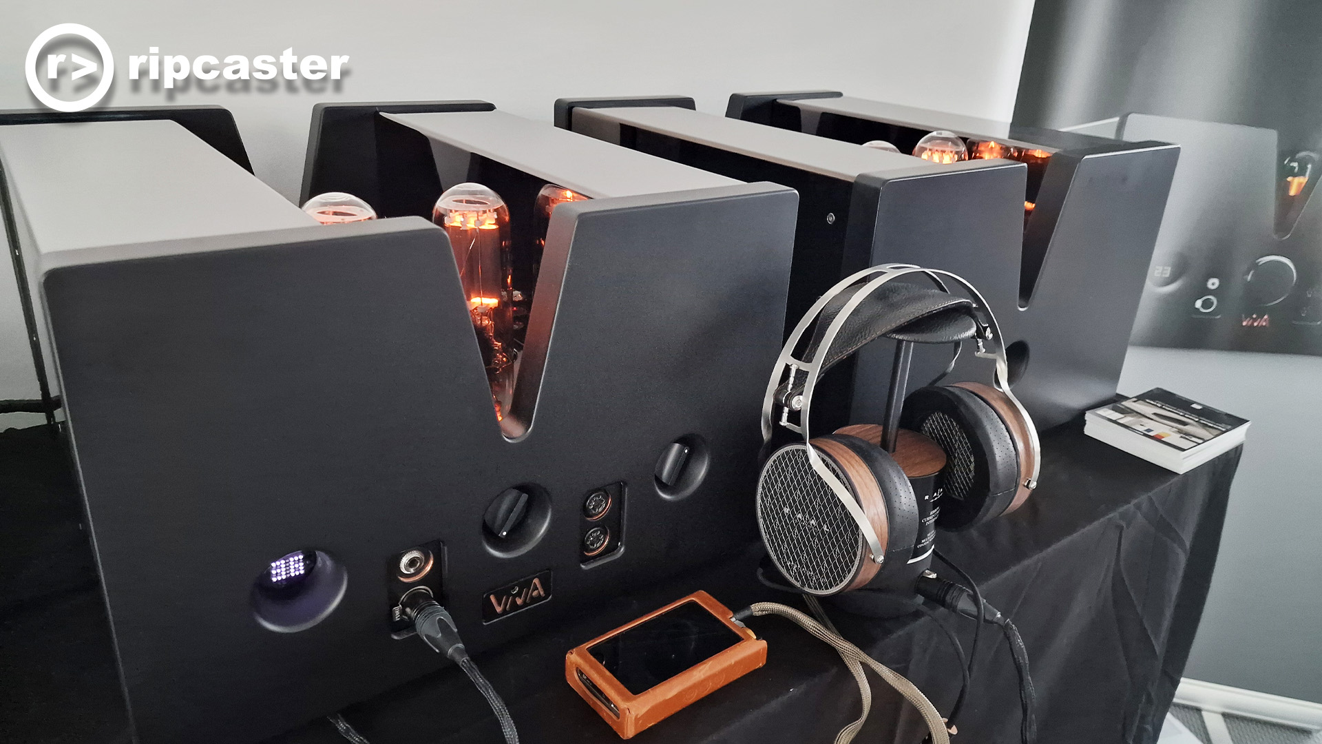 HiFi boxes with headphones on a stand in front of them.