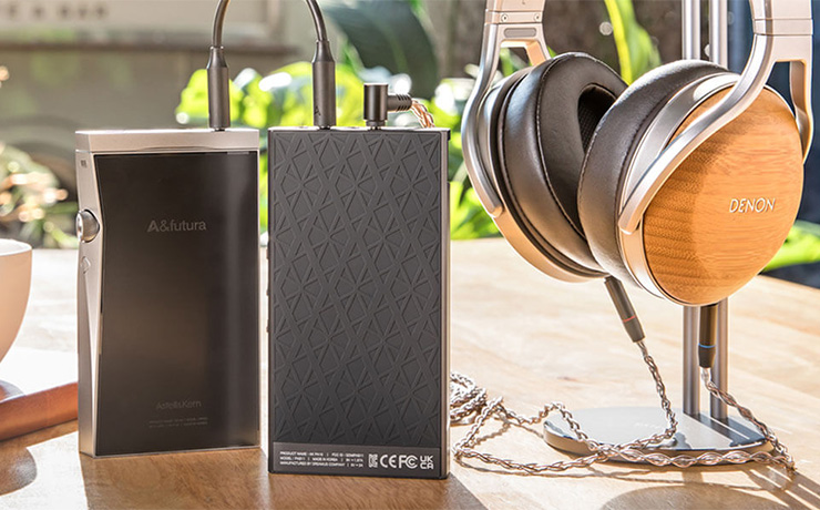 Astell & Kern AKPA10 Portable Class-A Amplifier connected to an A&K player with headphones plugged in and on a stand.