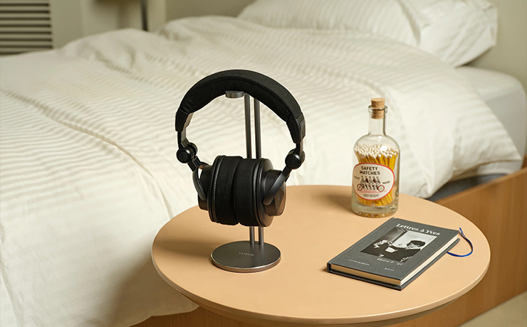 Astell & Kern Virtuoso Headphones on a stand with a bottle of something and a player on a circular table