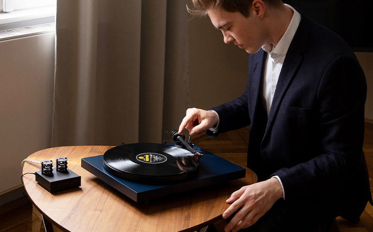 Project Debut Carbon EVO in navy on a table with a man putting the needle on the record