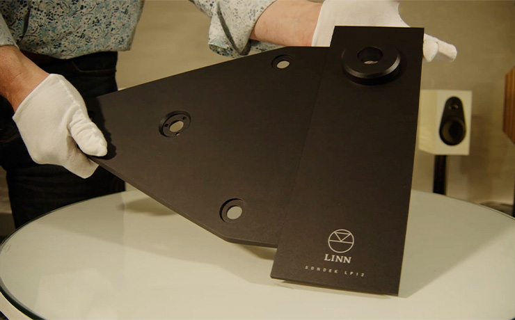 The Linn Keel SE in Jon's gloved hands being held at an angle. There's a Linn 119 speaker in white visible in the background