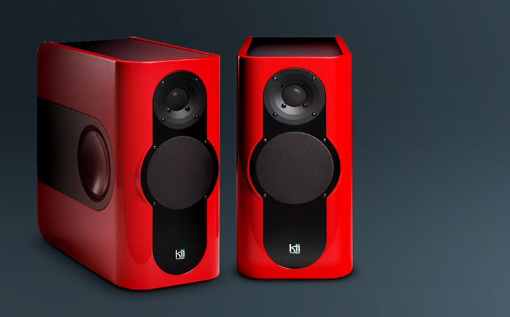 A pair of Kii Three speakers in red on a grey background