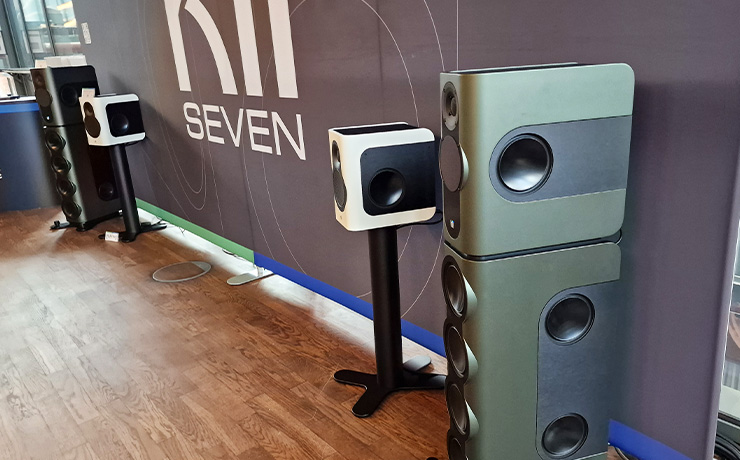 A pair of Kii Seven speakers in white with the larger Kii BXT speakers beside them.