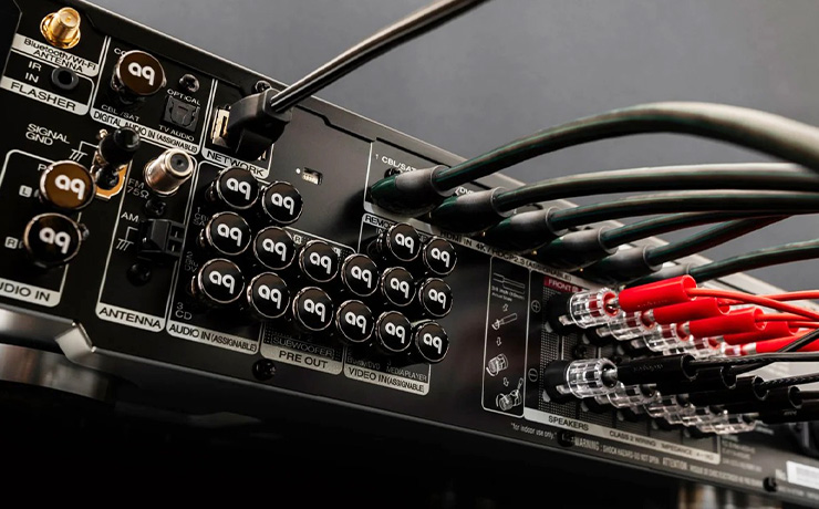 The back of a piece of audio equipment with many leads plugged into it and a lot of stoppers