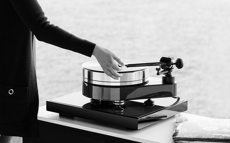 Project Signature 10 Turntable on a side unit with a woman putting the needle on a record