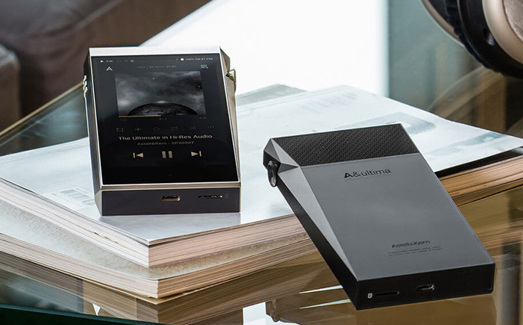 A&K SP2000T portable music player - two of them.  one viewed from the front and one laying face down.  On top of two thick A4 catalogues on a glass table
