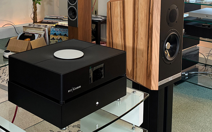 Ultrafide SP500 Stereo Power Amplifier on the top shelf of a HiFi rack with a Grimm MU2 stacked on top of it.  There's a Kudos 505 speaker on a stand beside it