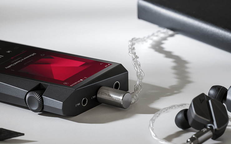 Astell & Kern A&norma SR35 Portable Music Player laying face-up with earphones plugged in