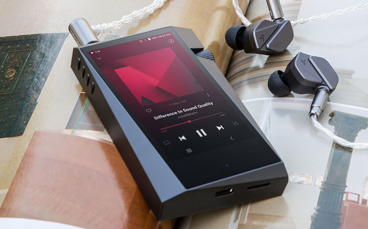 Astell & Kern A&norma SR35 Portable Music Player laying face-up with earphones beside it on an open book