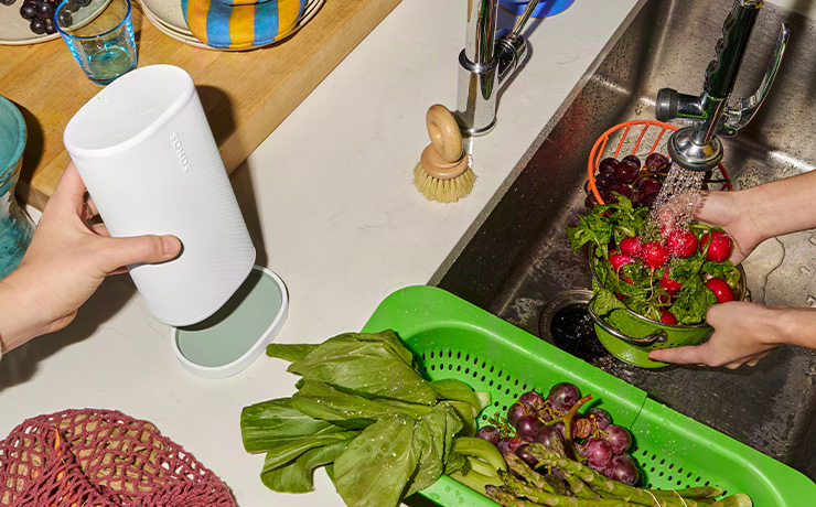 The Sonos Play in white being put onto its charging base on kitchen counter top