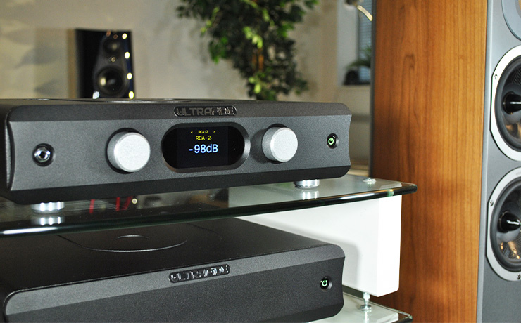 The Ultrafide U4PRE on the top shelf of a HiFi rack with the Ultrafide U500DC on the shelf below.  To the right of the rack is an Audiovector floorstanding speaker and you can see the top part of a Linn 360 speaker in the background 