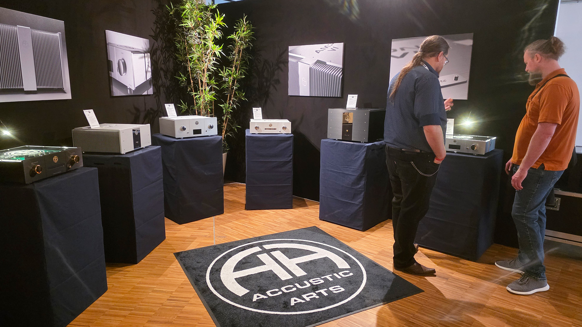 The Accustic Arts room at the HiFi Show in Vienna.  Two men are chatting in front of a piece of equipment on a plinth in the room