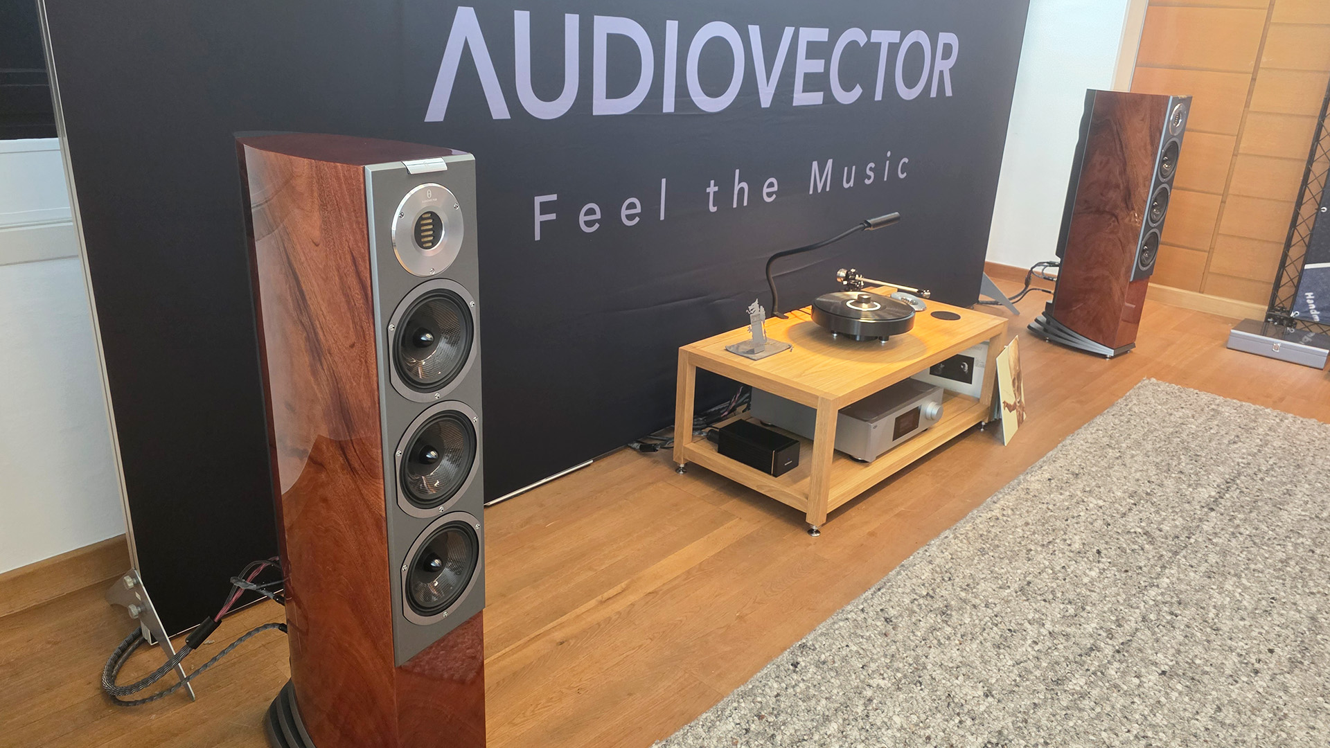 A pair of floorstanding Audiovector speakers with a turntable in between