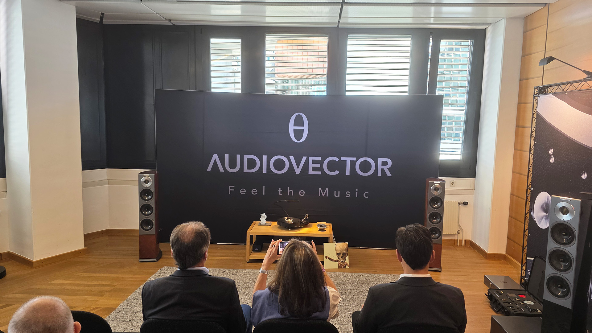 The Audiovector room with three people sitting with their backs to us