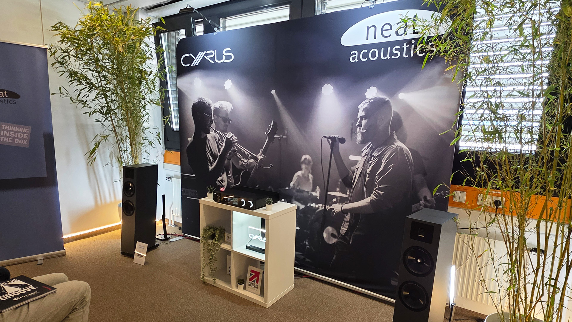 The Cyrus room with a large back drop and a pair of floorstanding speakers with a Cyrus unit in between