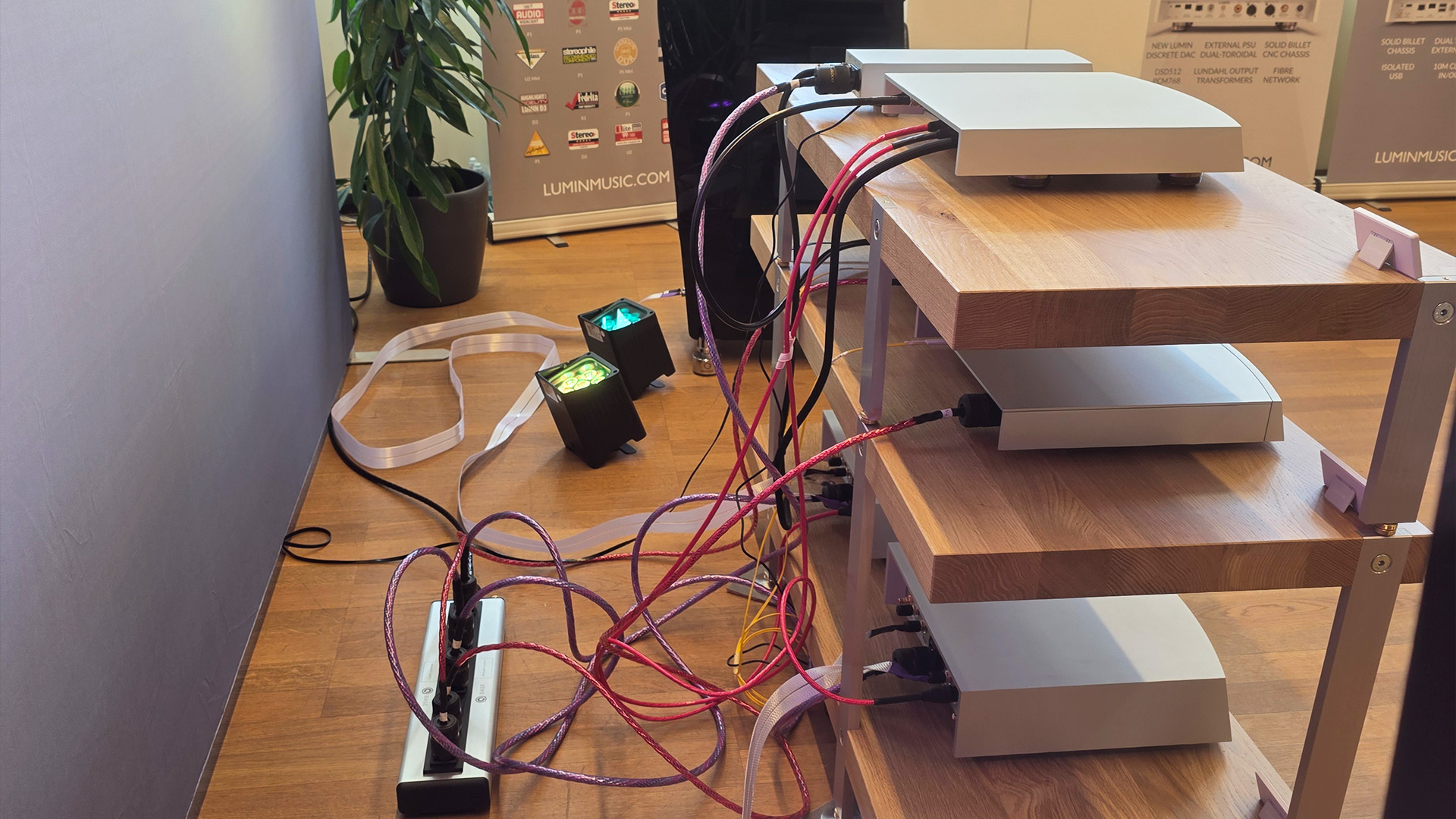 A selection of Lumin units on a wooden HiFi unit - a view of the back with various colourful Nordost cables