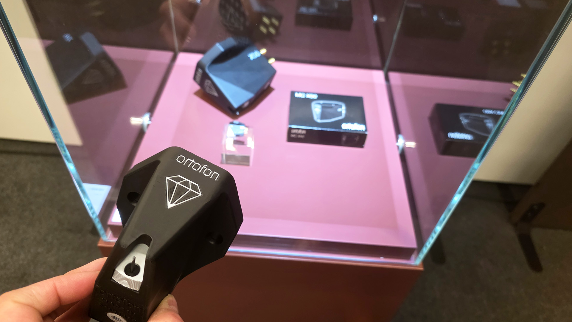 An Ortofon cartridge being held in front of a cabinet