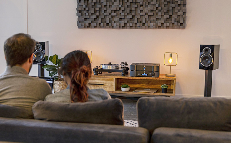 Voice 22 loudspeakers in a living space with two people on a sofa who can be seen from behind