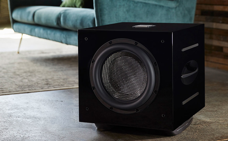 REL Carbon Special subwoofer on the floor of a living space with a sofa in the background