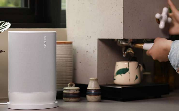 A white Sonos Move 2 speaker on a kitchen counter beside a coffee machine