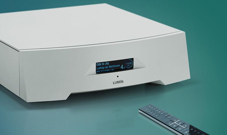 Lumin P1 Network Music Player on a green background with the remote control in front of it