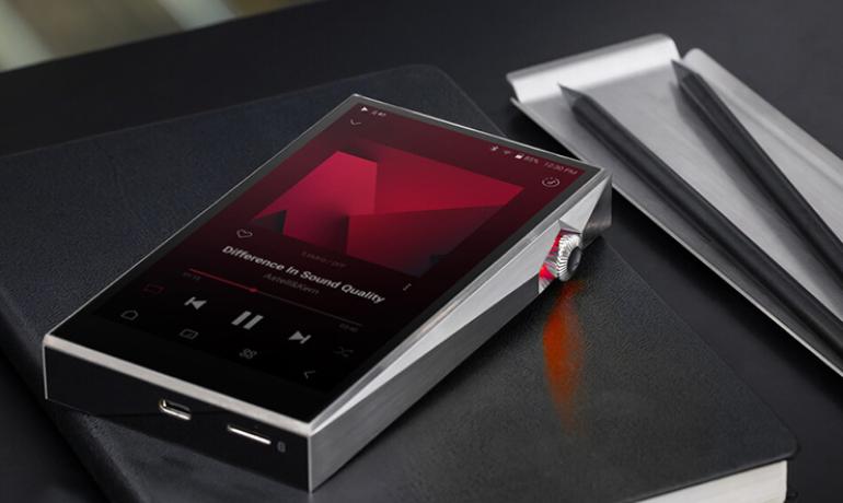 Astell & Kern SP3000T Music Player laying face-up.  There's a metal tray with two pencils to the side