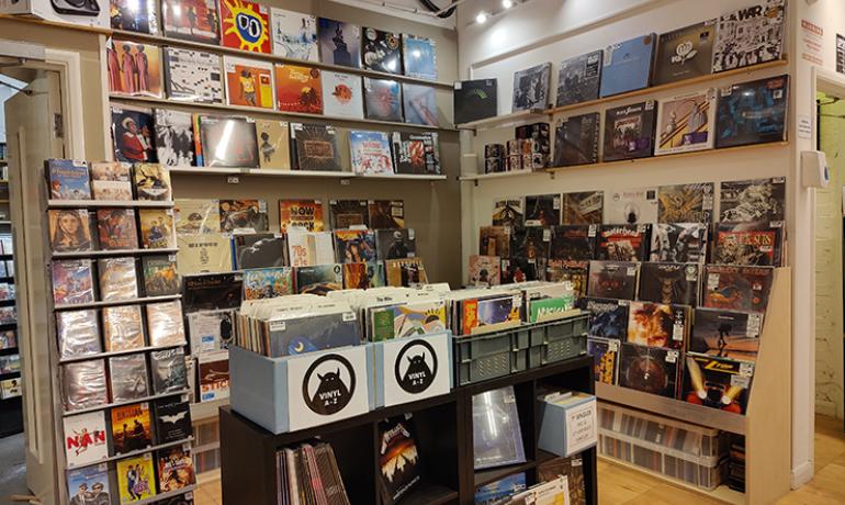 Image shows record covers all over the walls and in bins in hte centre of the room.  