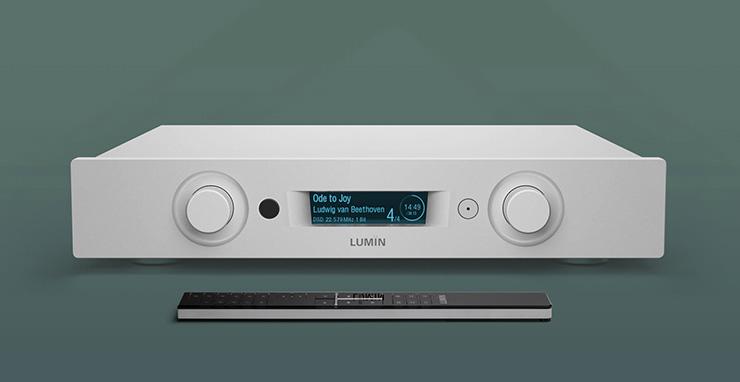 Lumin P1 Mini - Streamer, DAC, Pre-Amp in silver on a green background with a remote control in front of it.