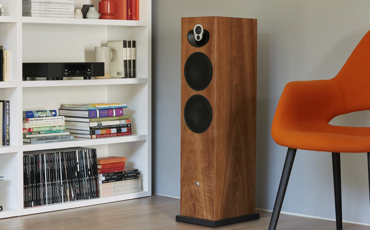 Linn Majik 140 Loudspeaker beside an orange chair and, on the other side, a bookcase.