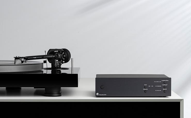 Project Phono Box S3 B on a sideboard beside a turntable