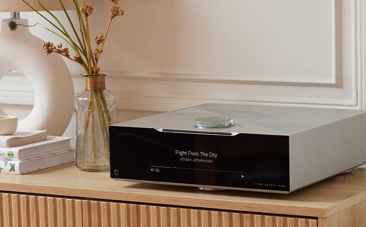 The Linn Selekt DSM Classic Hub 2024 on a wooden side unit with a vase beside it