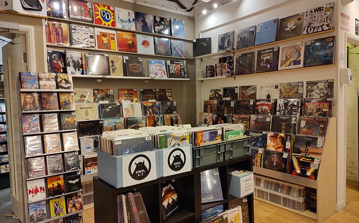 This image shows a corner of a record store.  There are shelves and racks of records.  It looks very well stocked.