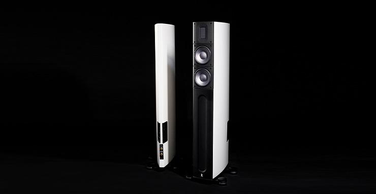 A pair of Raidho X2t speakers in white.  One facing front, one facing so the rear is visible